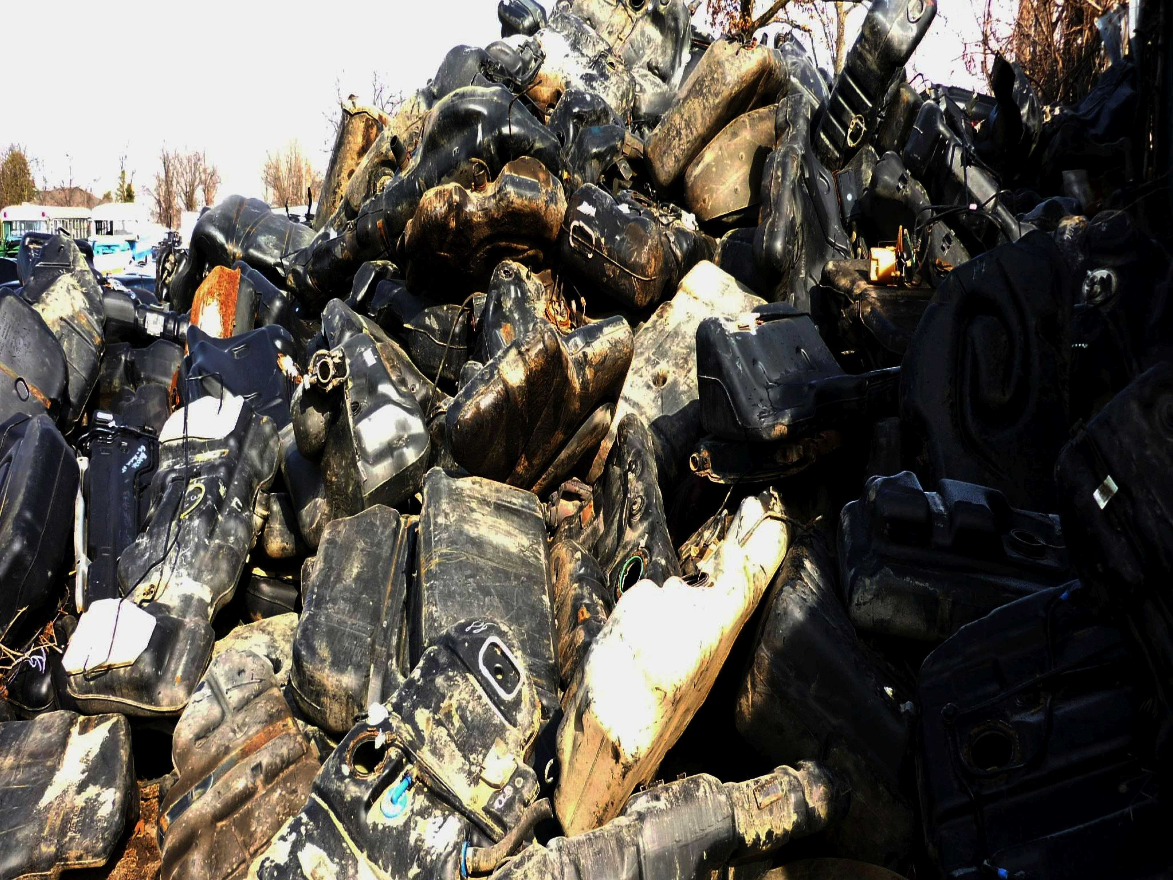A pile of old cars and motorcycles in a parking lot