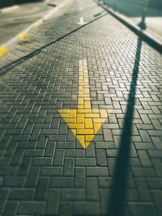 A yellow arrow painted on a brick road