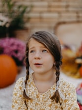 A little girl sitting on the ground looking up