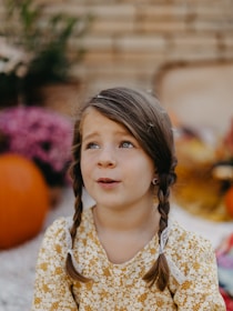 A little girl sitting on the ground looking up