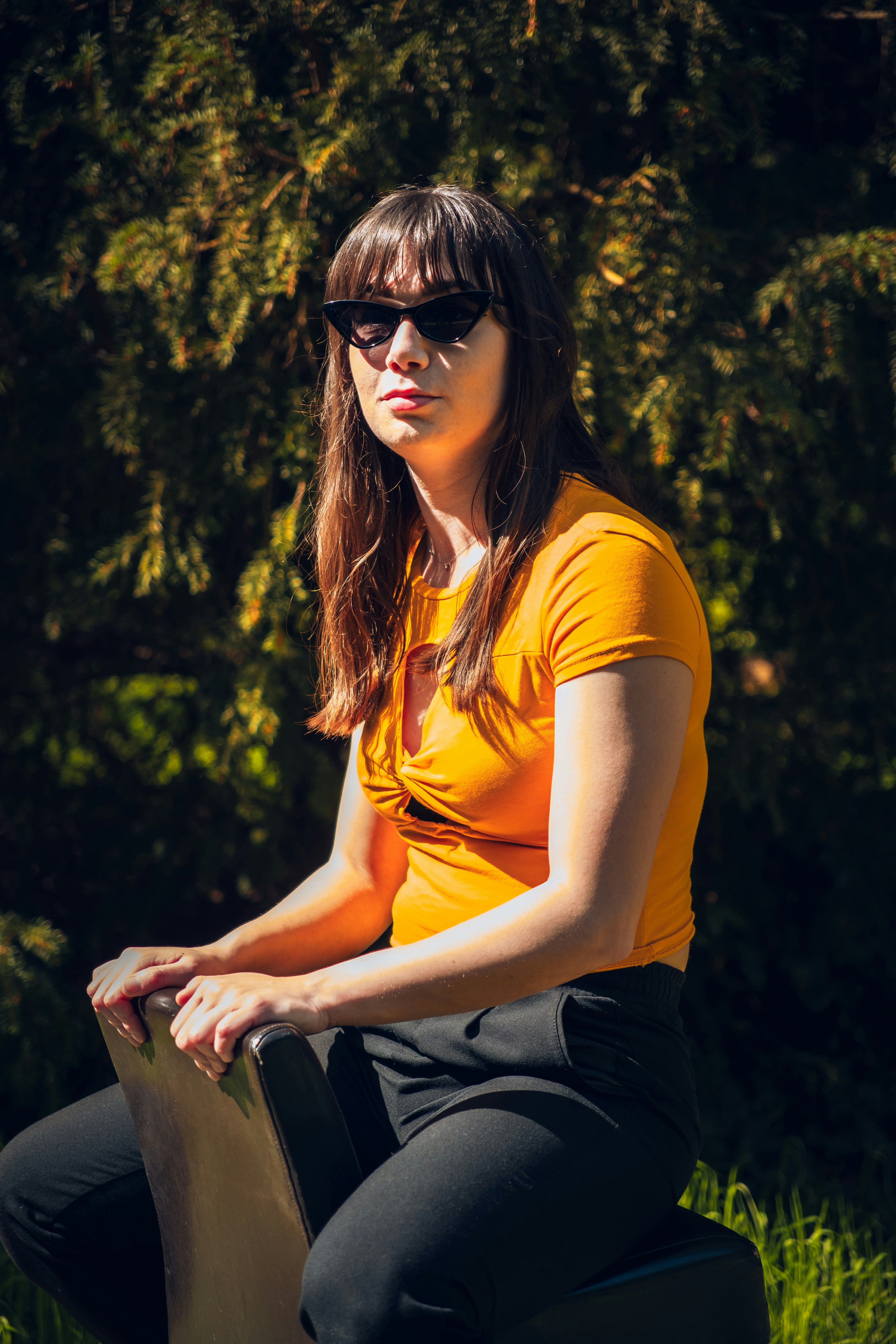 A woman in a yellow shirt and black pants holding a skateboard