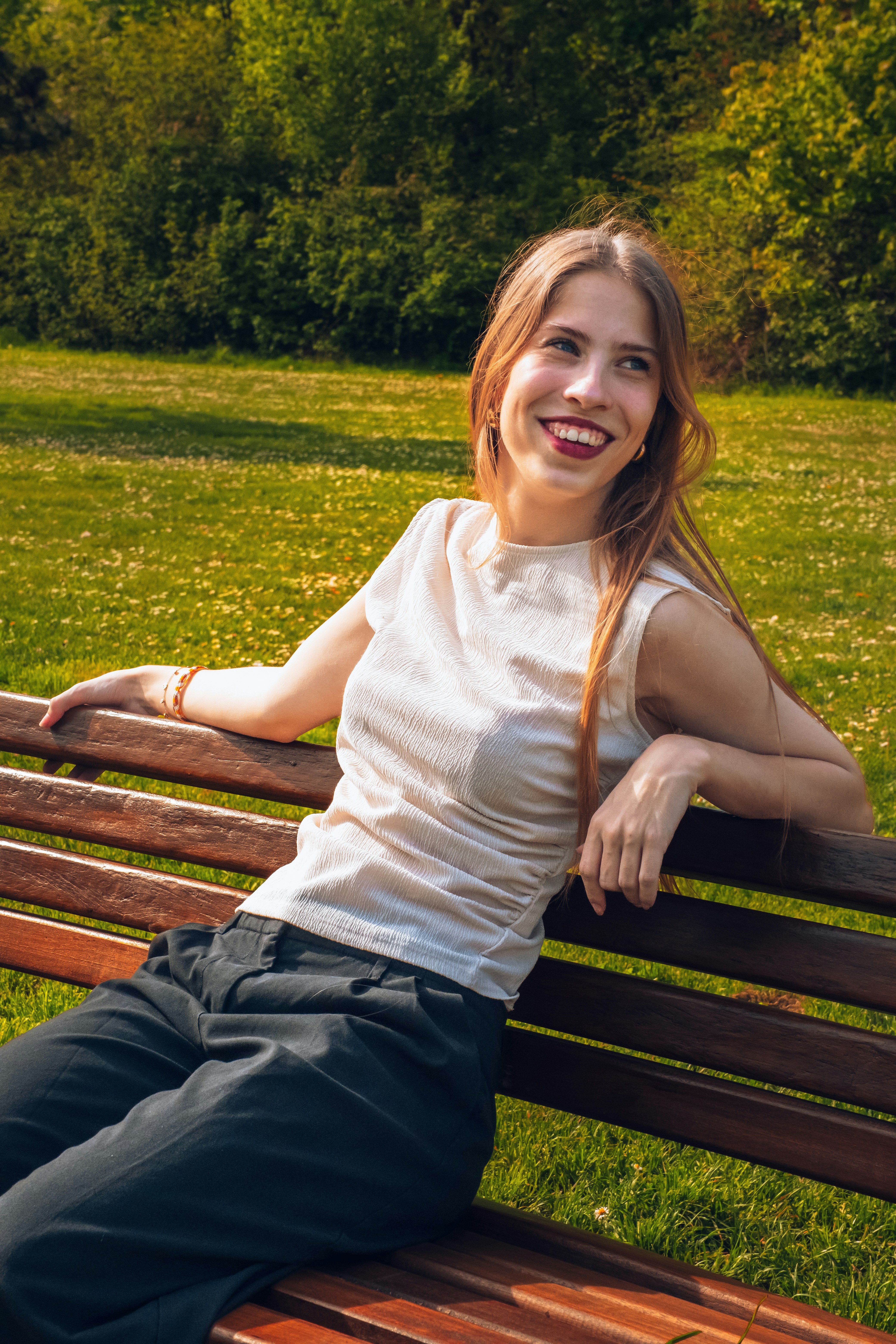 A woman sitting on a wooden bench in a park