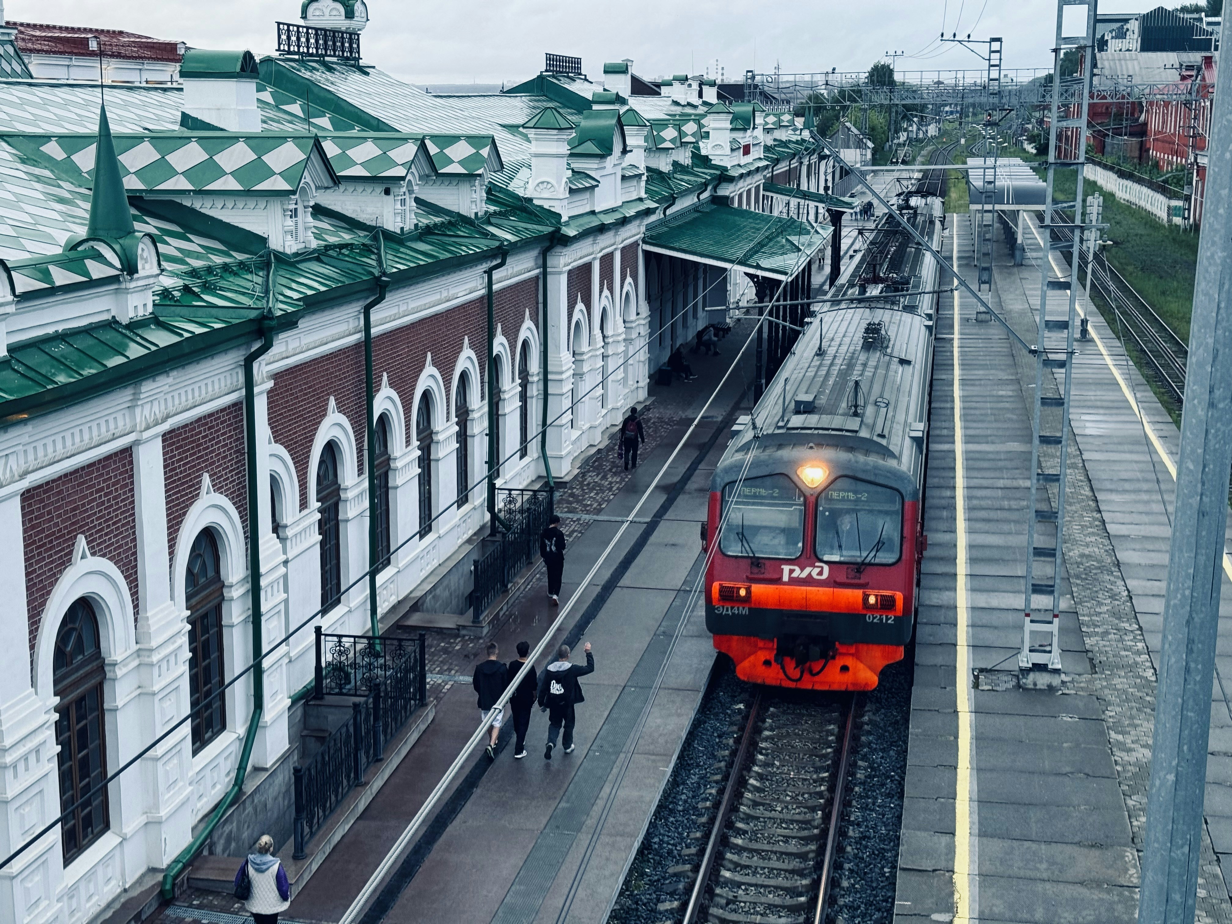 A red train traveling down train tracks next to a train station