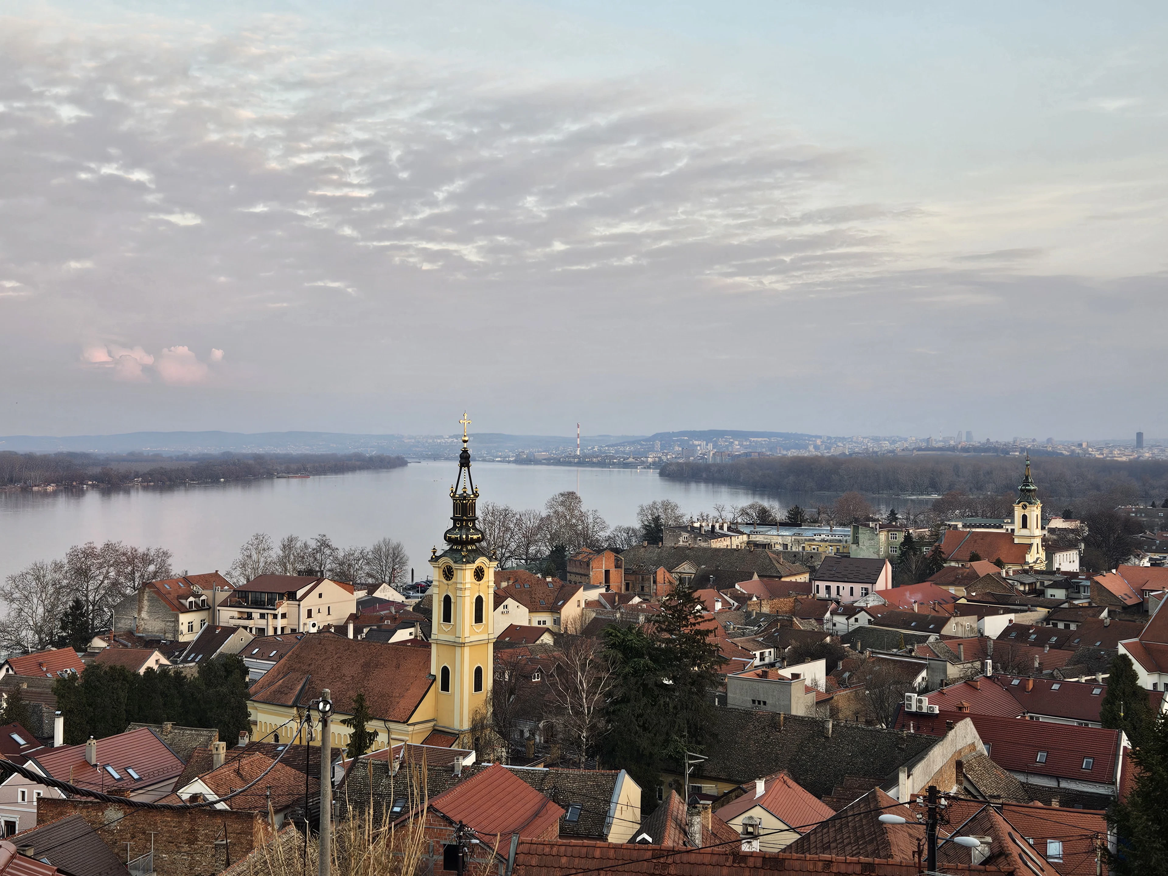 Zemun's Gardoš tower rising above red-roofed houses with the Danube behind at dusk