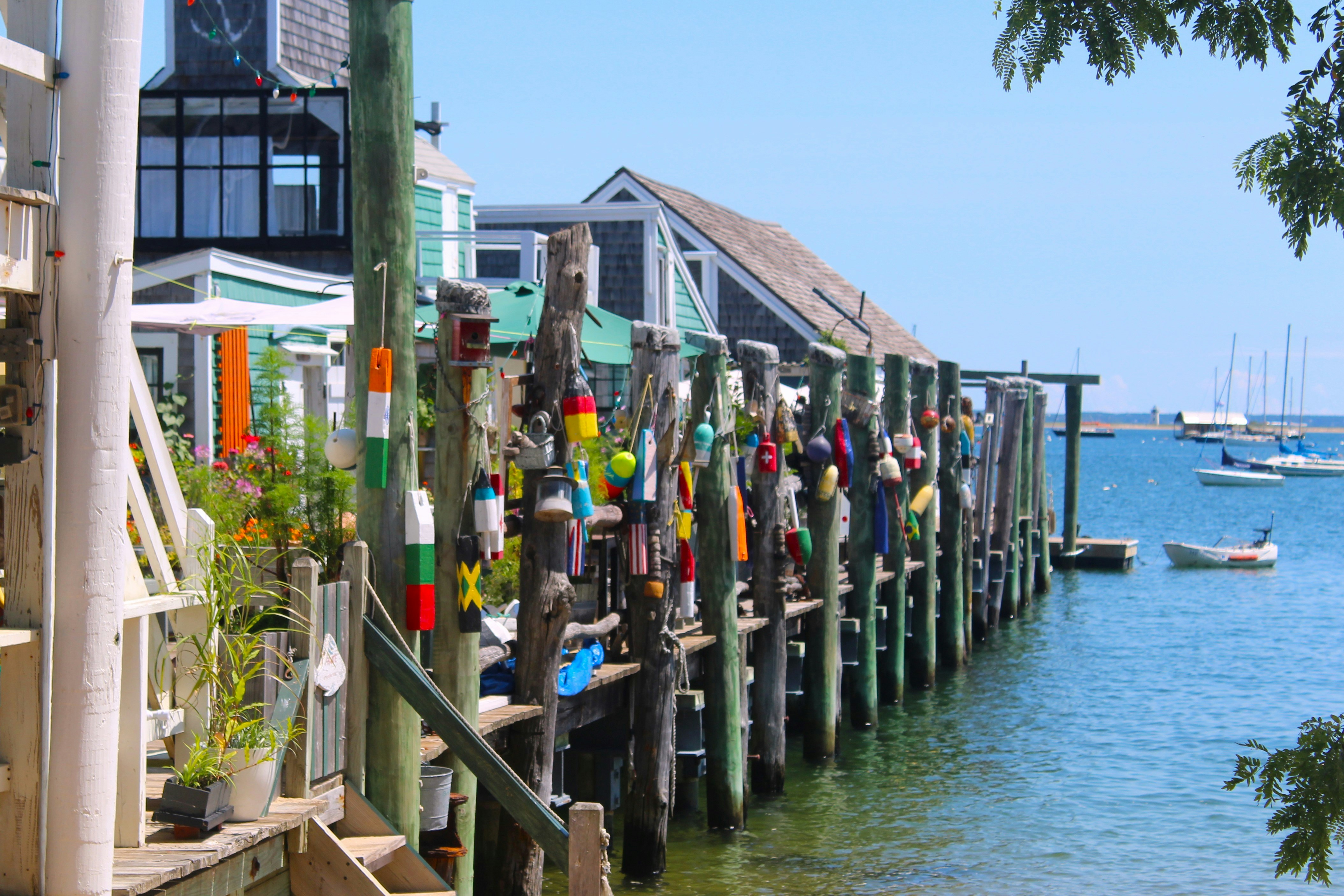 A group of people standing on a dock next to a body of water