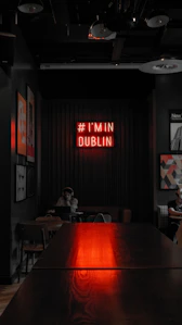 A long table in a dark room with a neon sign on the wall