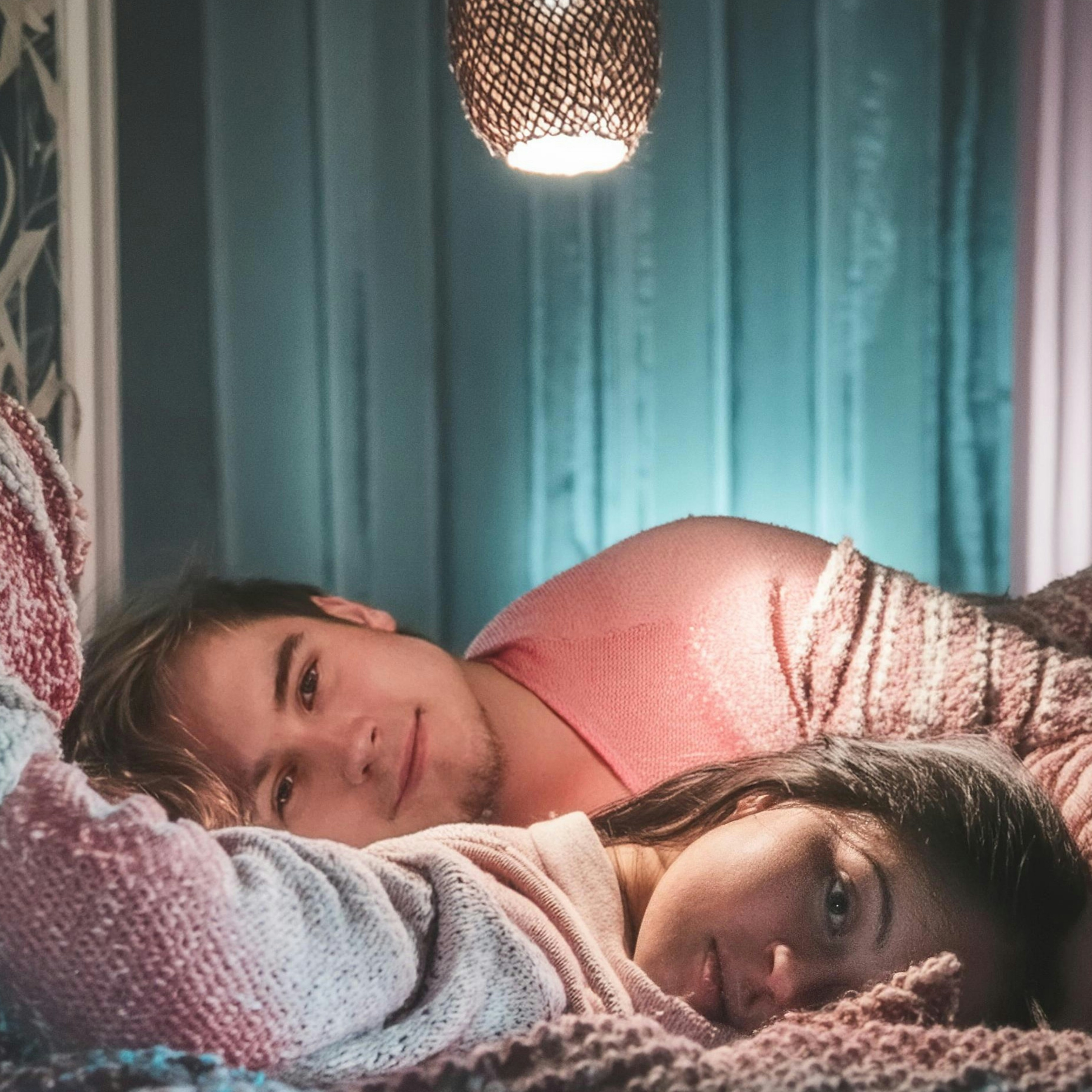 A couple of women laying on top of a bed