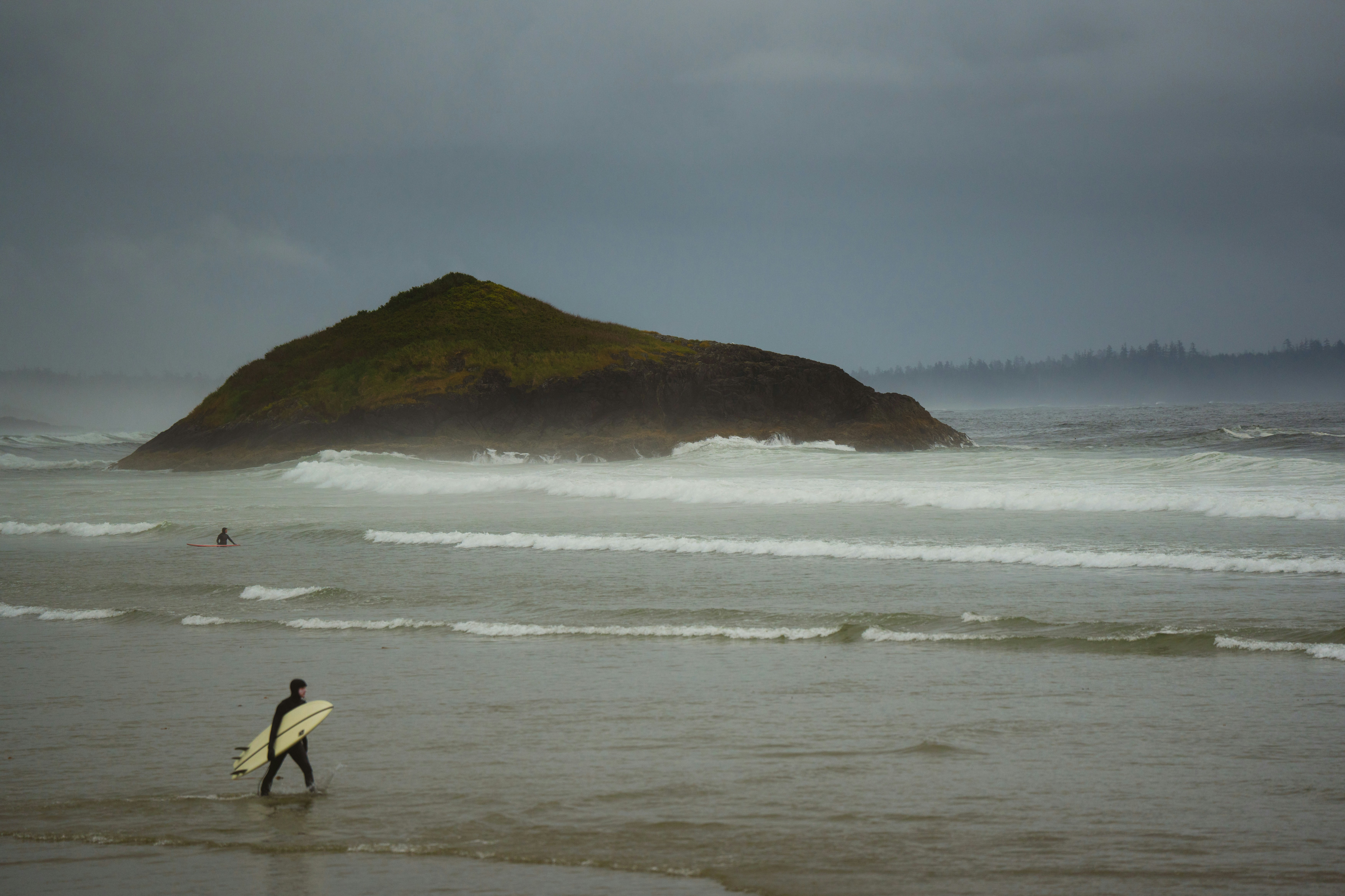 A person walking on a beach with a surfboard