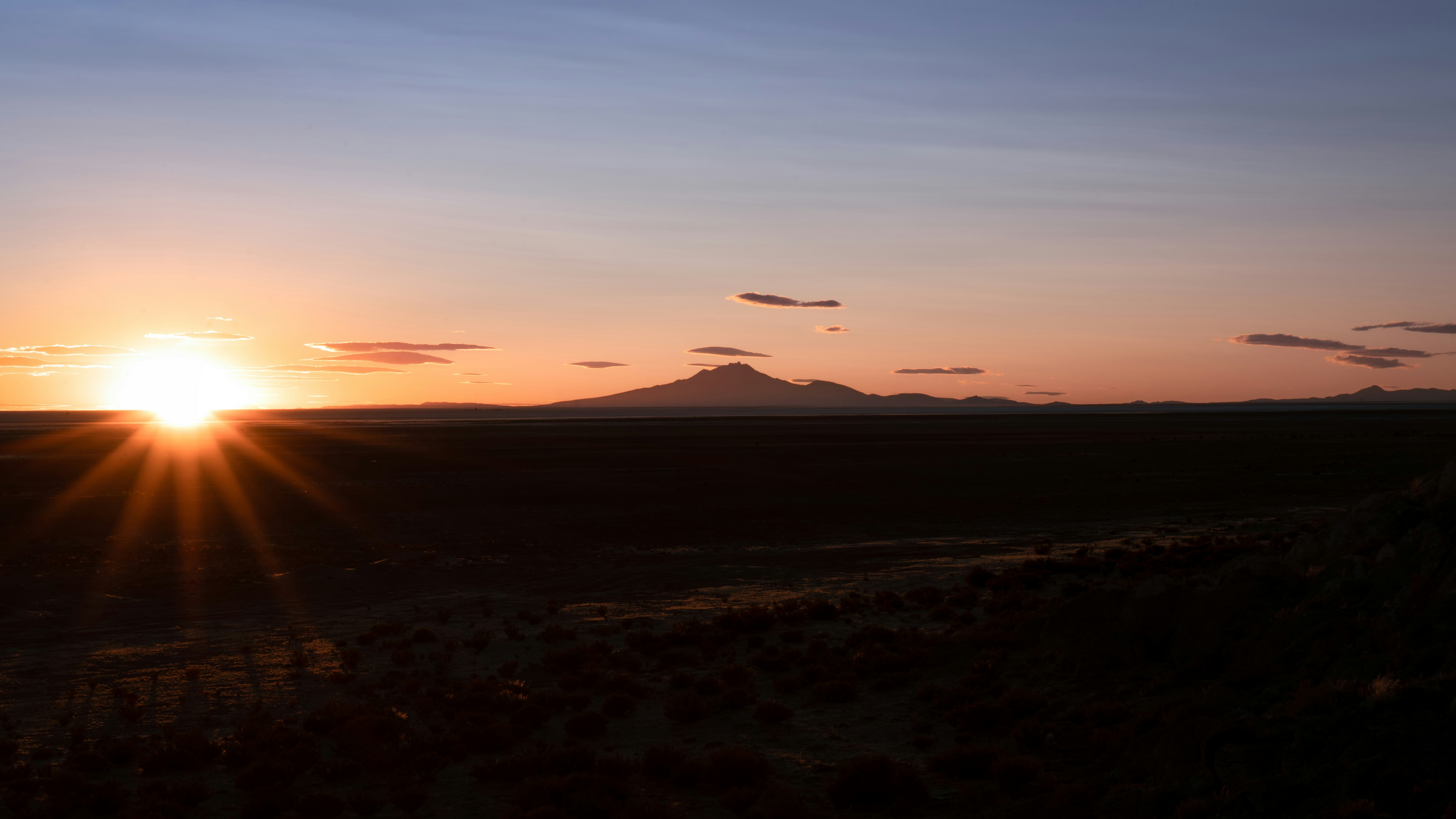 The sun is setting over the mountains in the distance