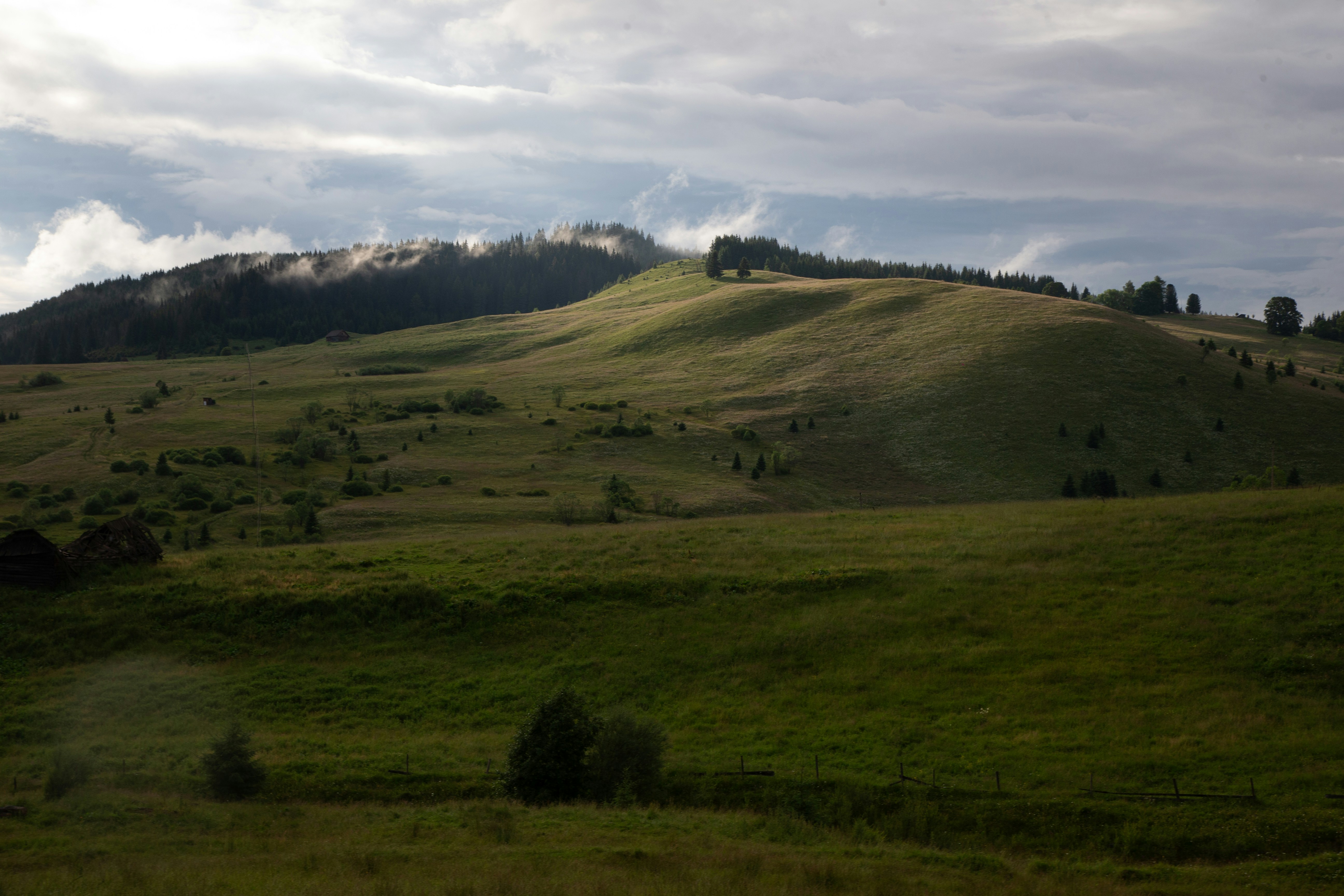 A lush green hillside covered in clouds and trees