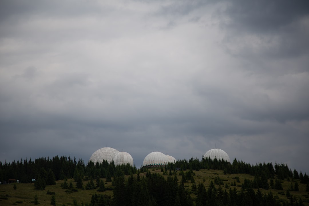 A group of large white domes sitting on top of a lush green field,