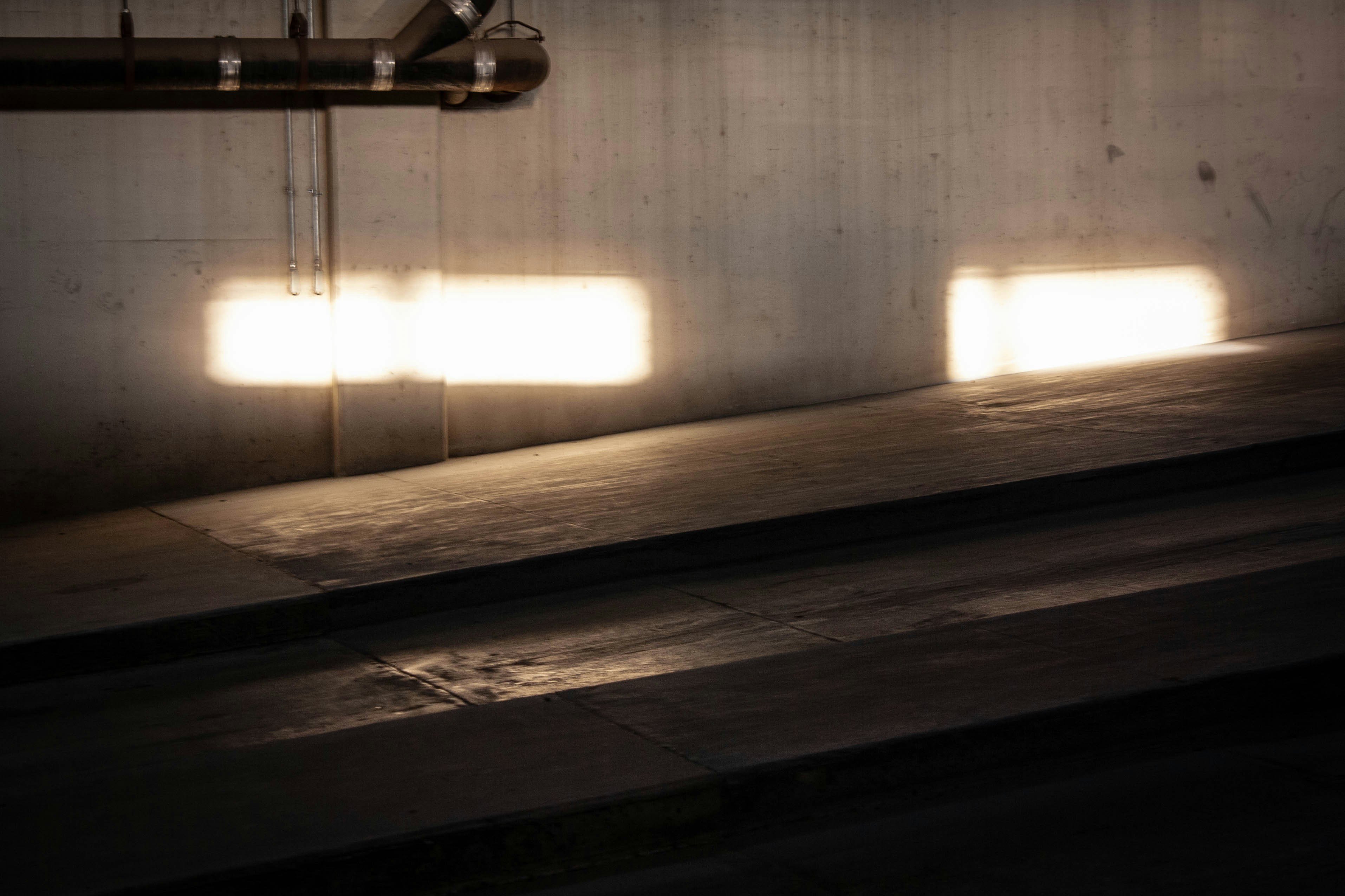 A dark room with three windows and a pipe