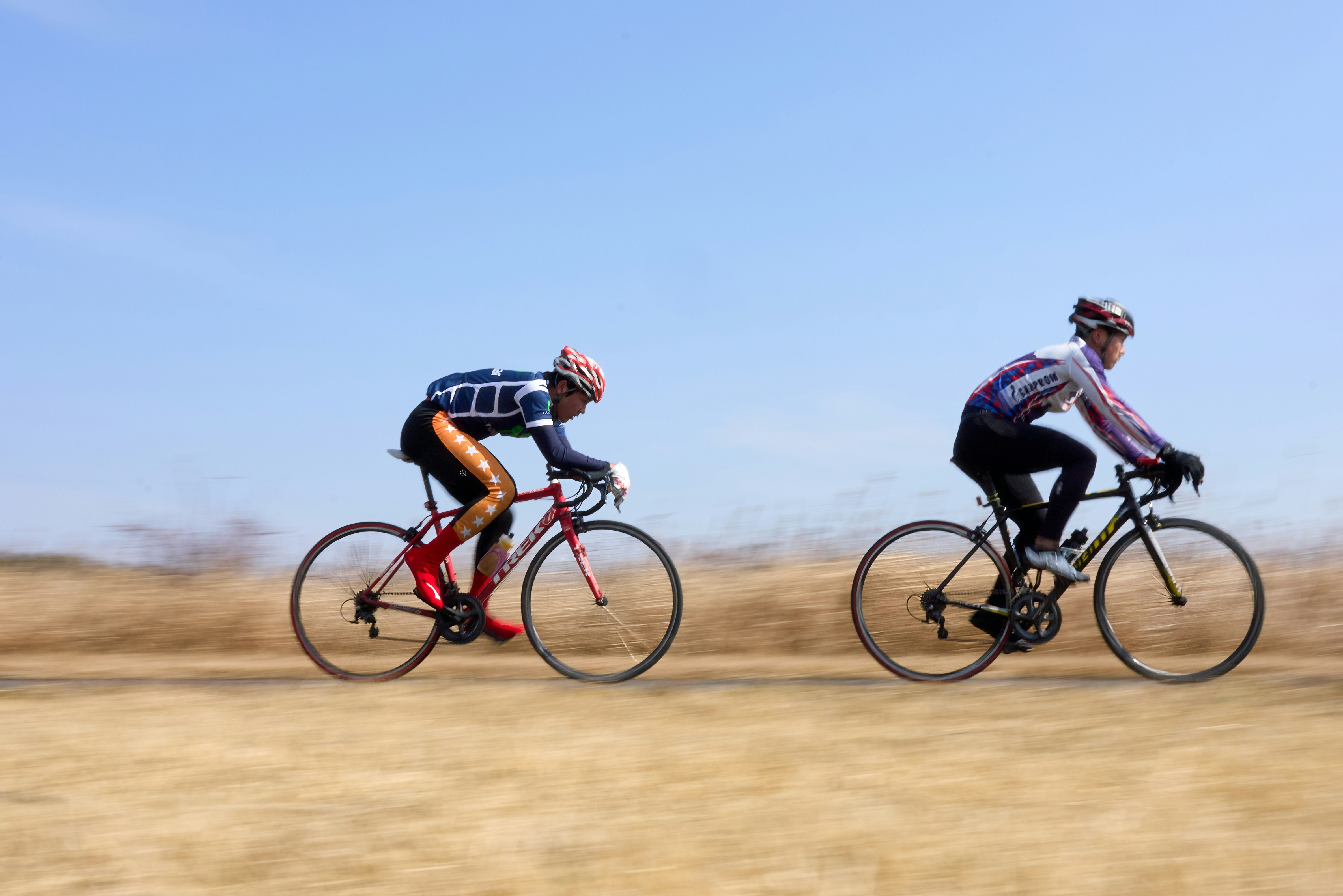 A couple of men riding bikes down a dirt road