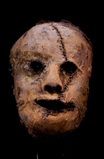 An old mask with a creepy face on a black background