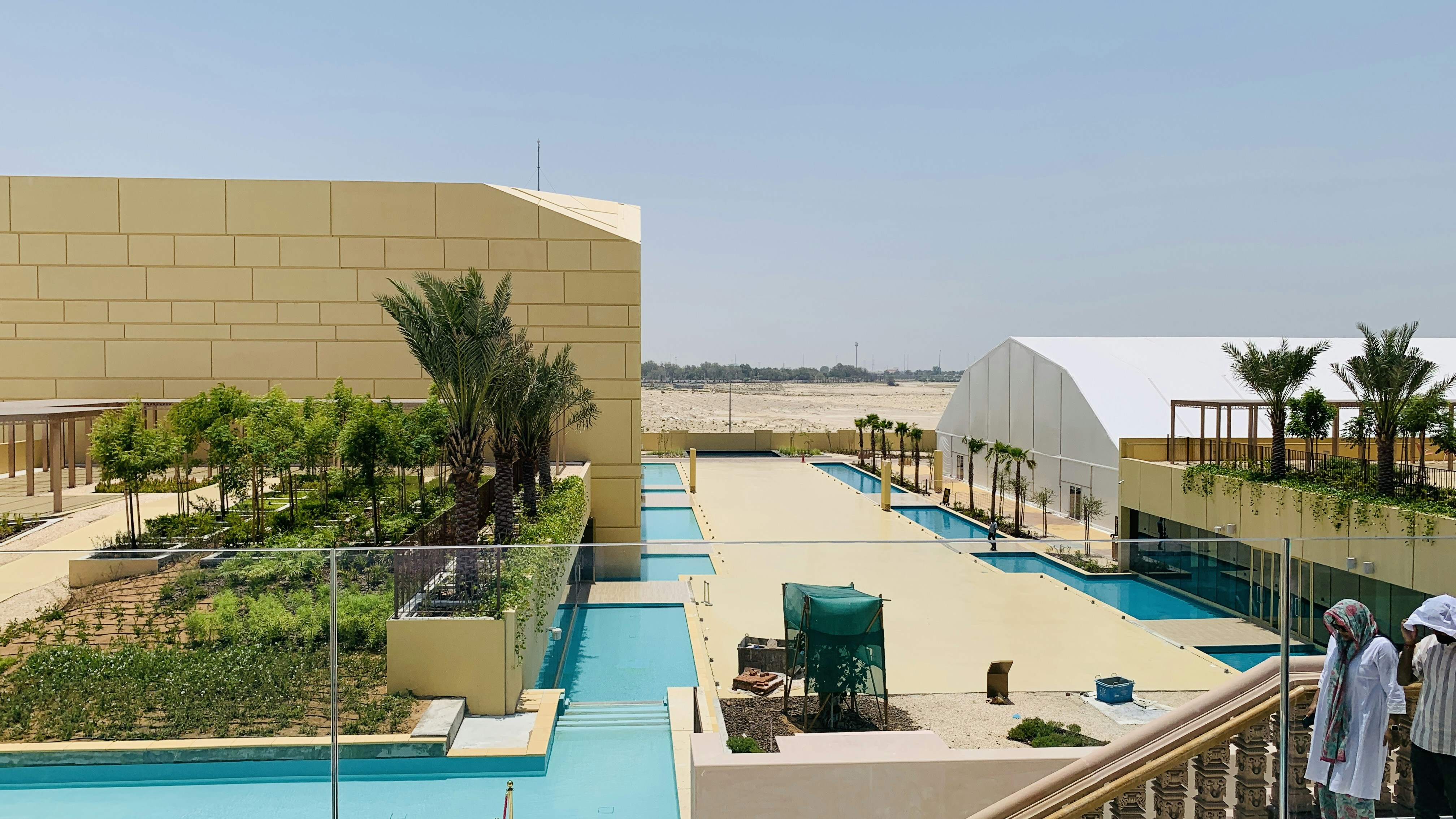 A group of people standing on a balcony next to a swimming pool