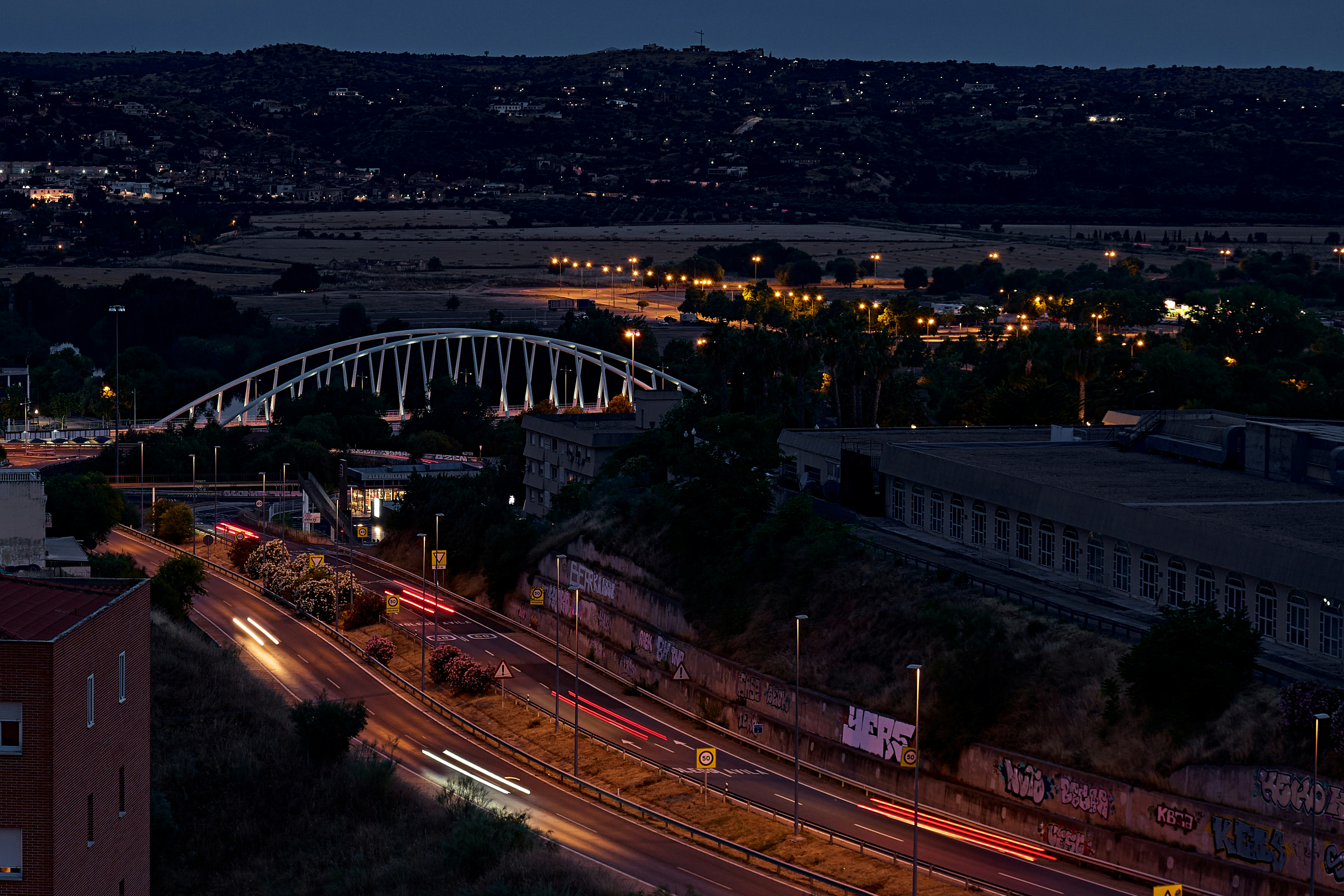 A view of a city at night with a bridge in the background