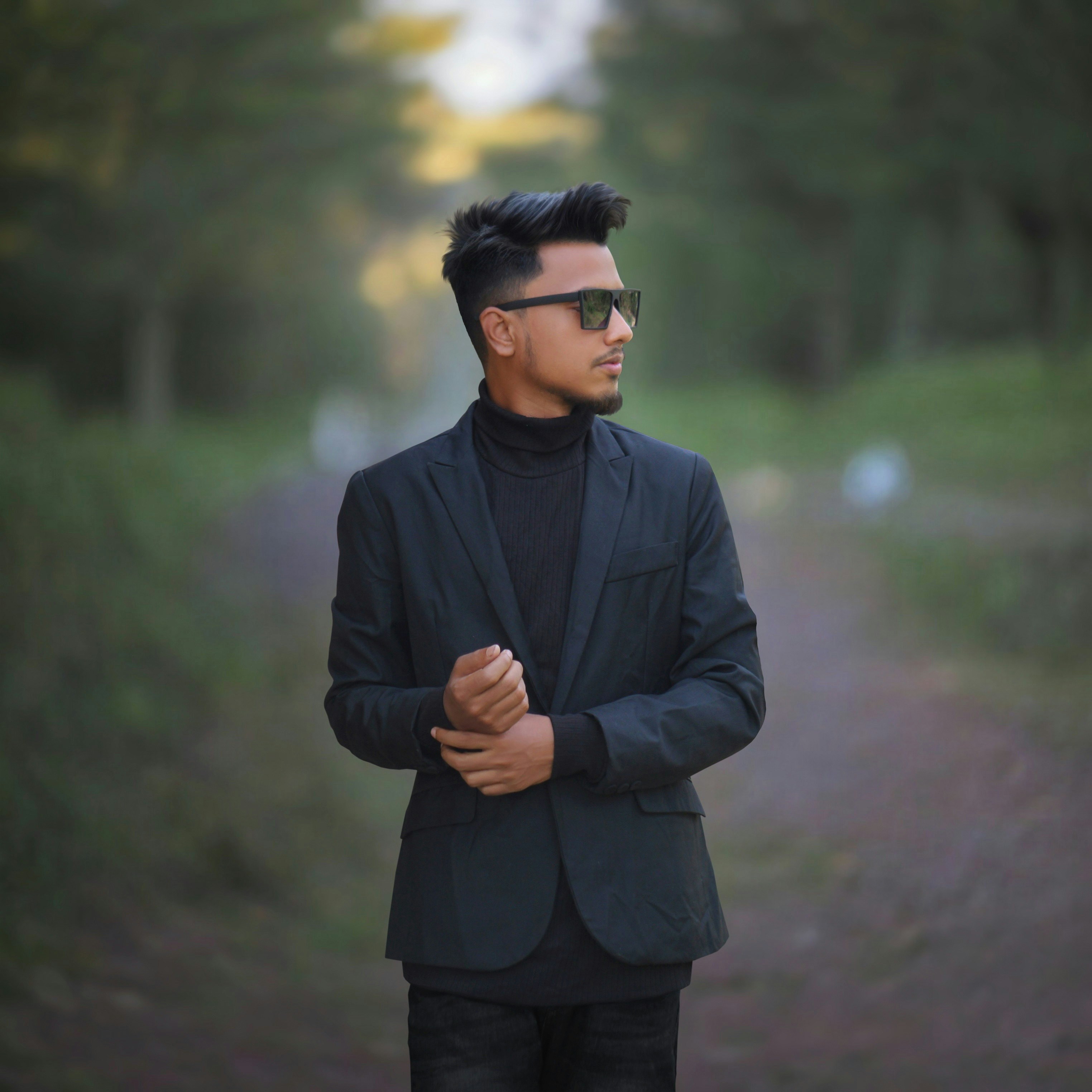 A man standing on a dirt road wearing a suit