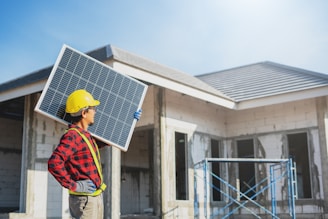 A man holding a solar panel in front of a house