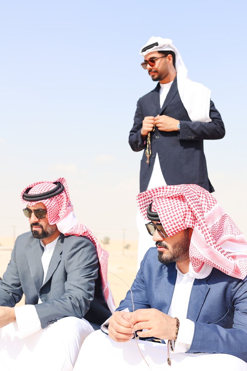 A group of men sitting on top of a sandy beach