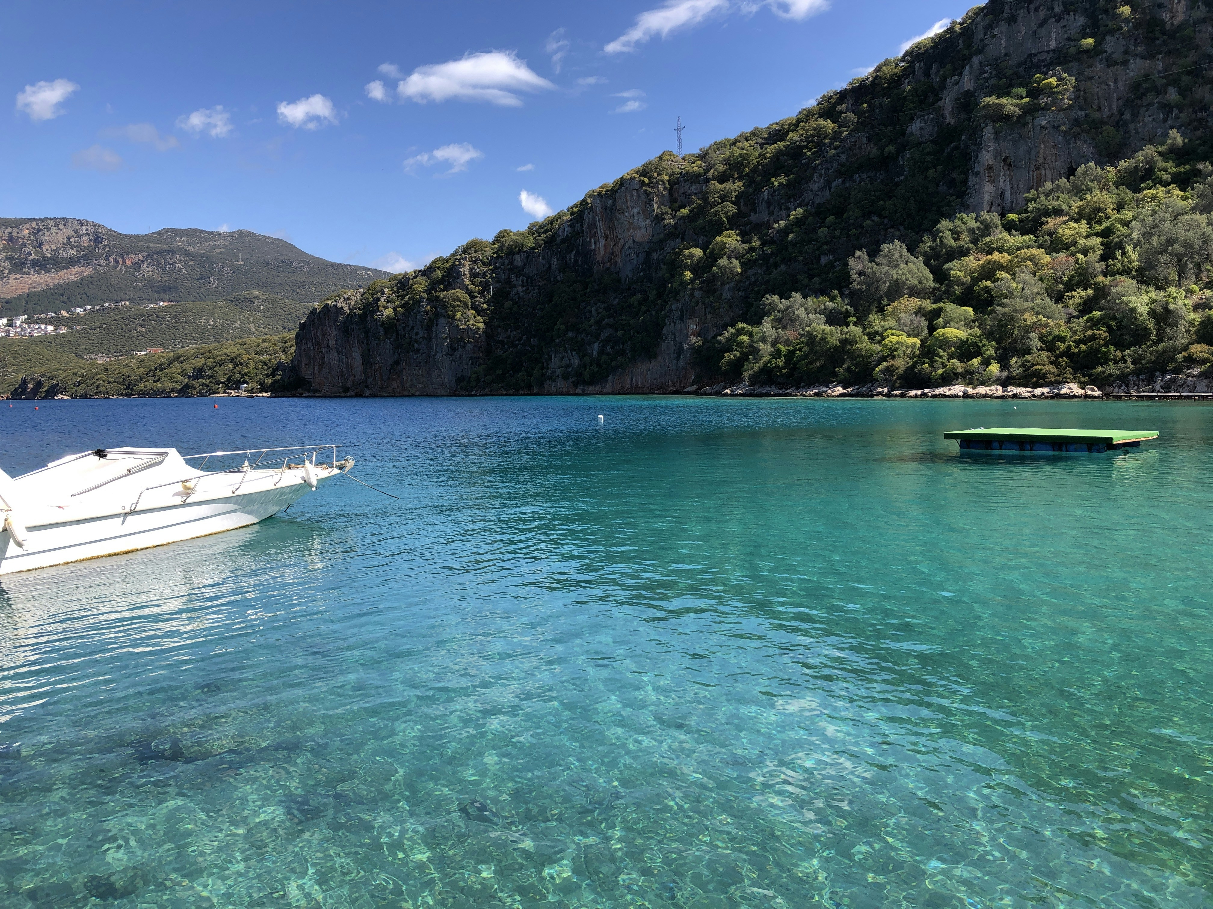 A boat floating on top of a lake next to a mountain