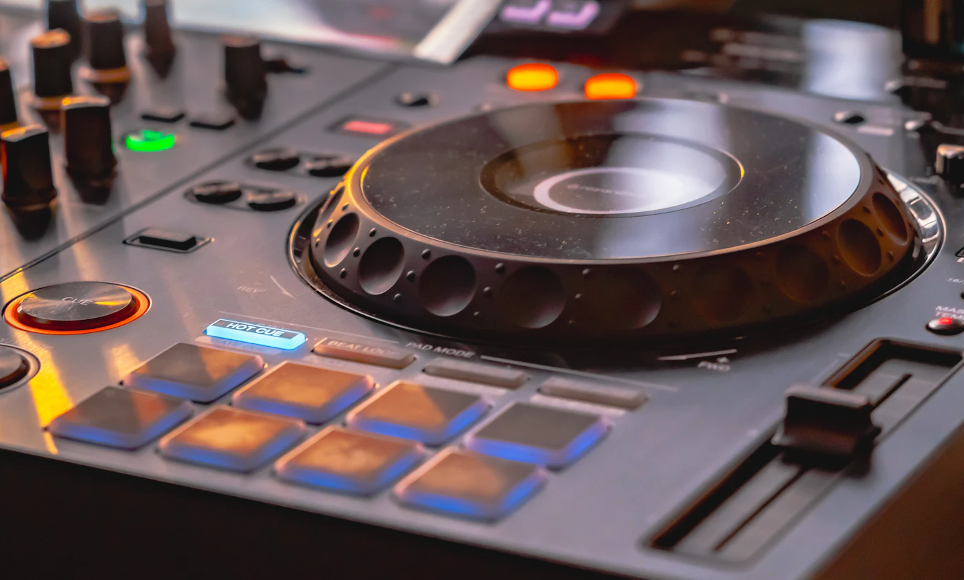 Close-up of a professional DJ controller jog wheel, pads, and mixer controls
