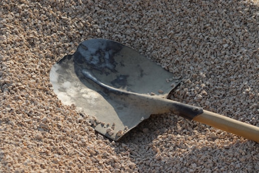 A shovel laying on top of a pile of sand
