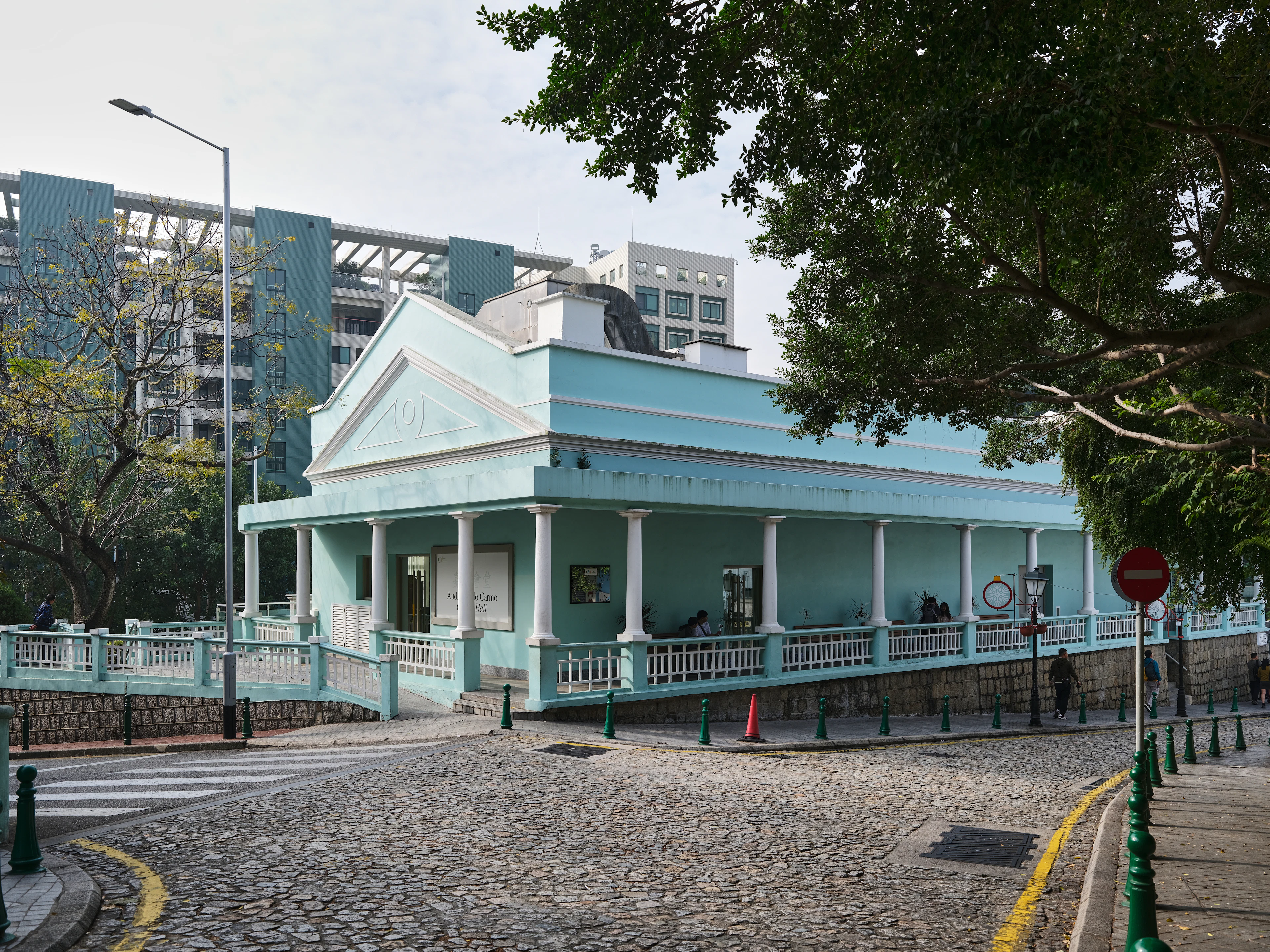 A mint-green colonial-era house with a veranda on a cobbled street in Macau