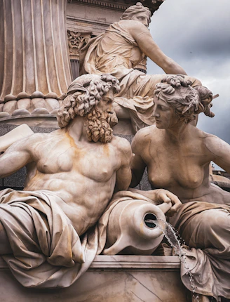 A statue of two men and a woman sitting on top of a fountain