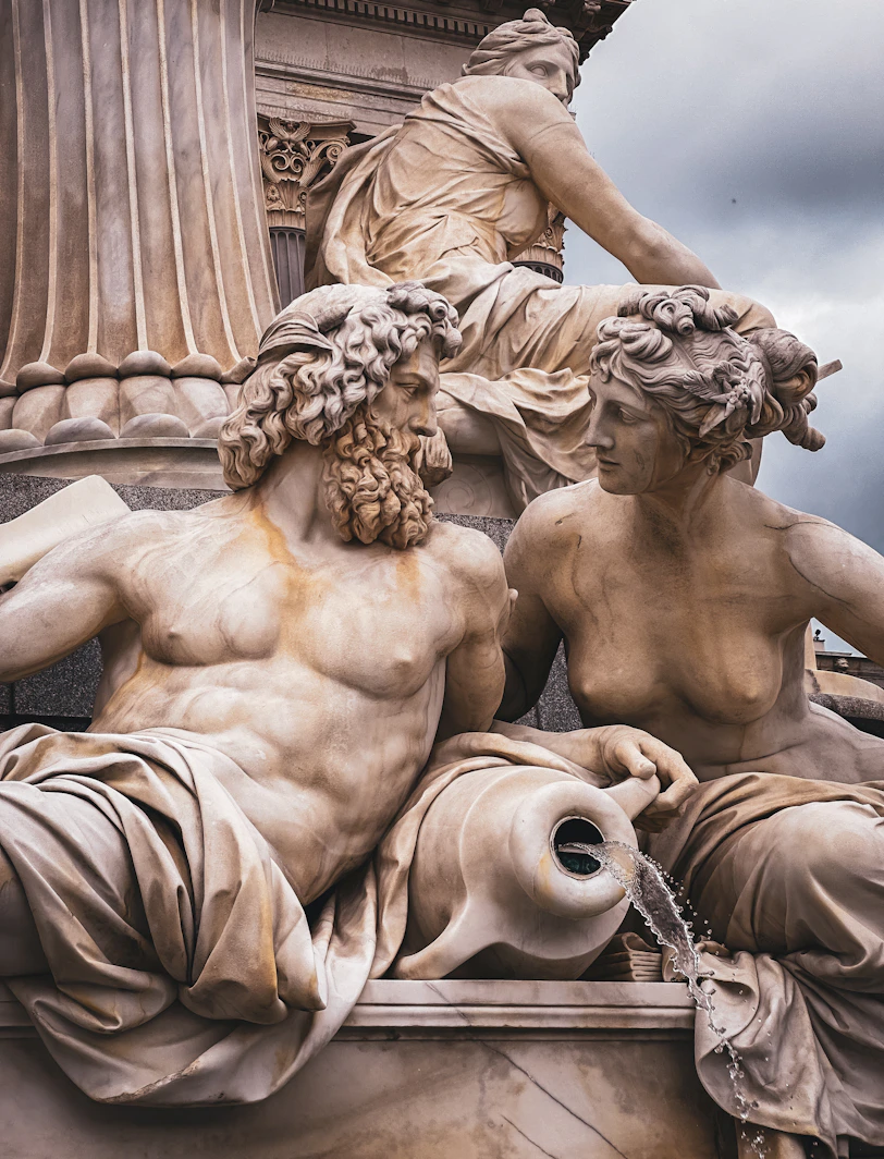A statue of two men and a woman sitting on top of a fountain