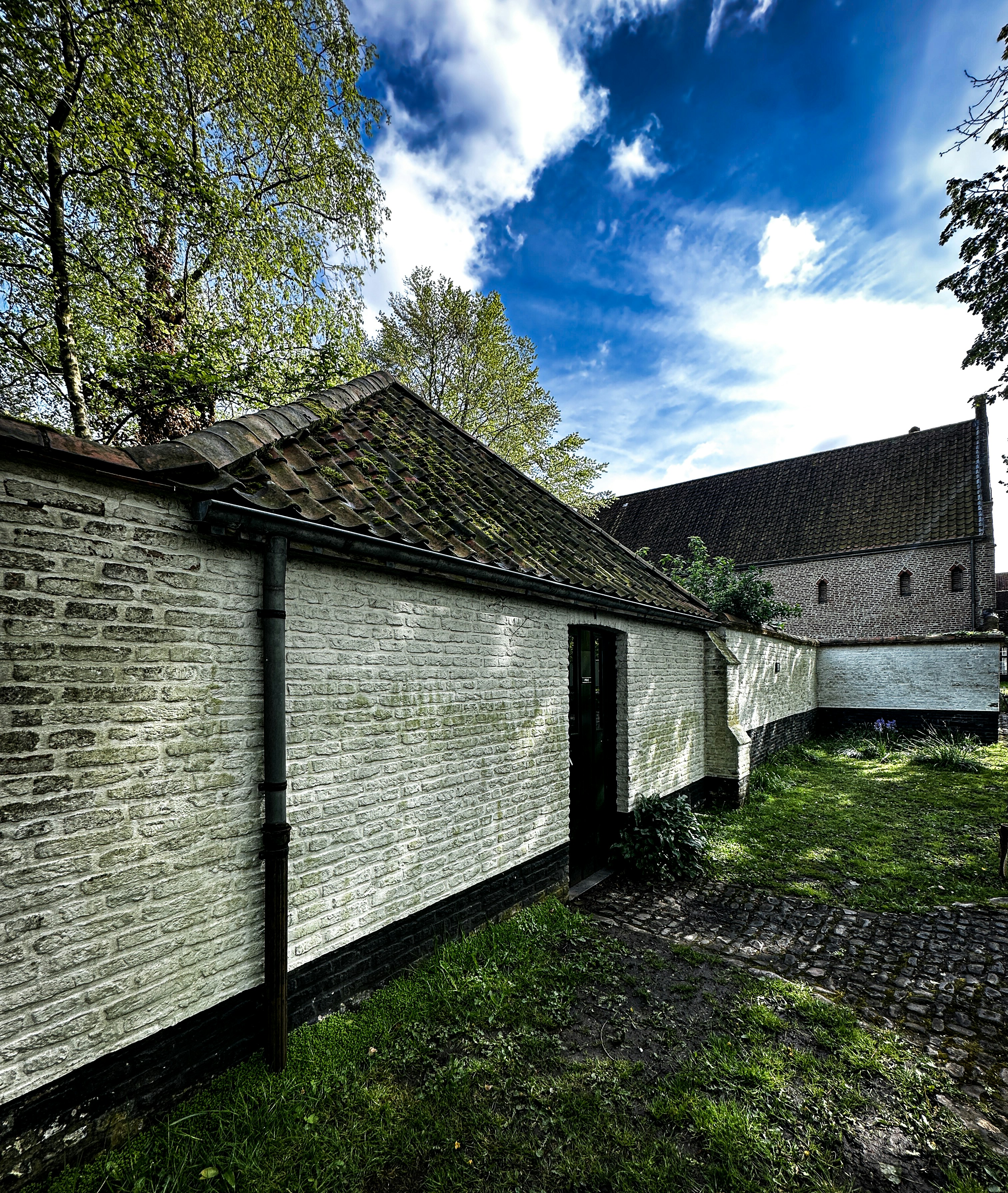 A brick building sitting next to a lush green field