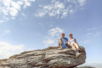 Two men sitting on top of a large rock