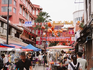 A group of people walking down a street next to tall buildings