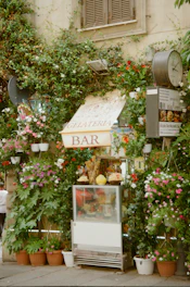 A small bar with a bunch of flowers on the side of a building