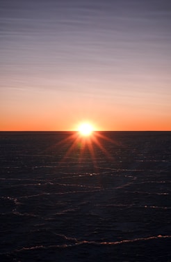 The sun is setting over the ocean on a clear day