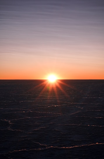 The sun is setting over the ocean on a clear day