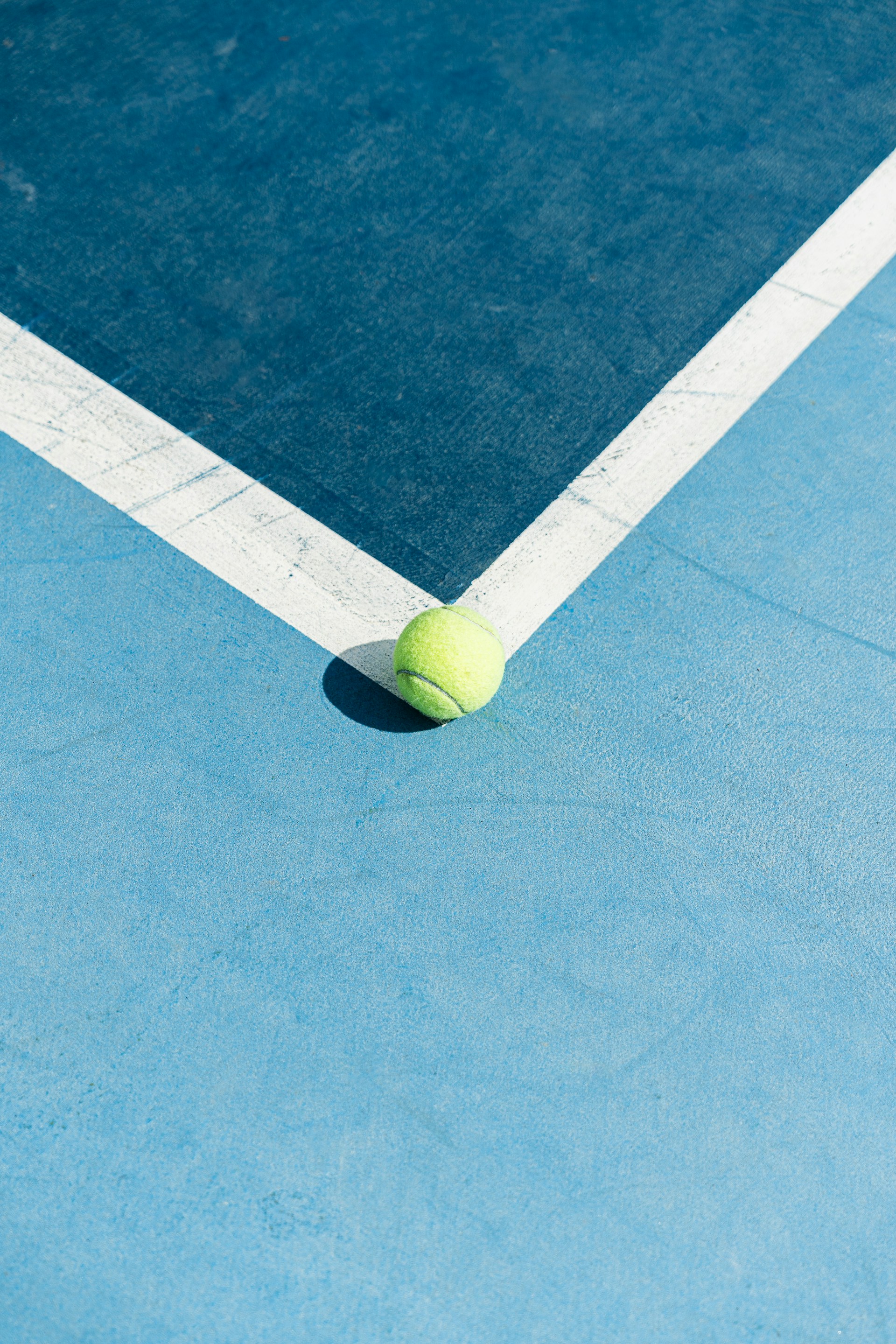 A tennis ball on a blue tennis court