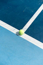 A tennis ball on a blue tennis court