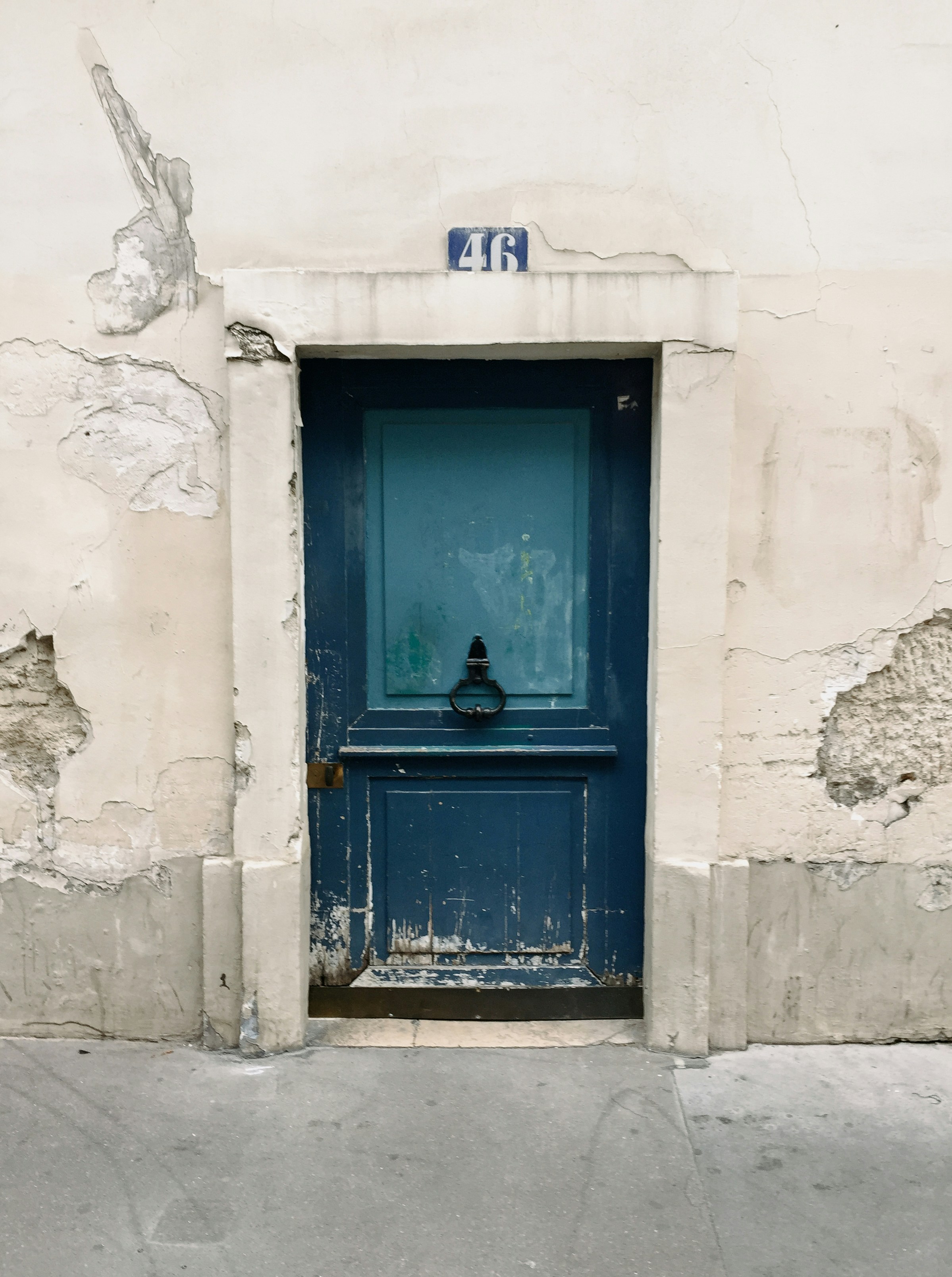 A blue door on a white building with peeling paint