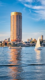 A sailboat on the water in front of a tall building