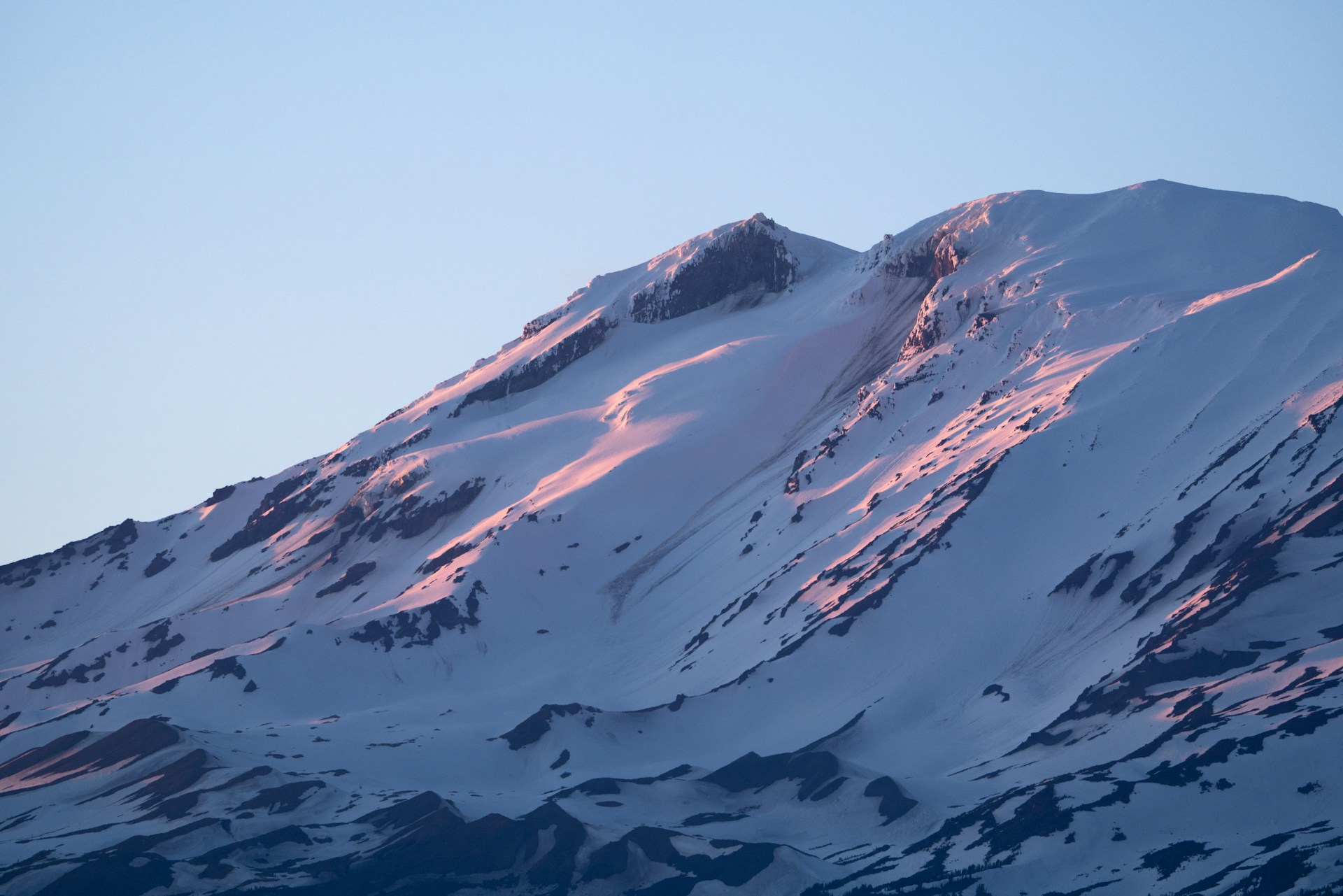 A large mountain covered in snow under a blue sky