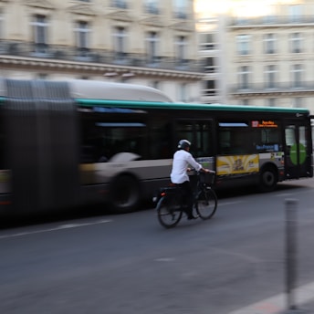 A man riding a bike down a street next to a bus