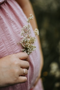 A pregnant woman in a pink dress holding a flower