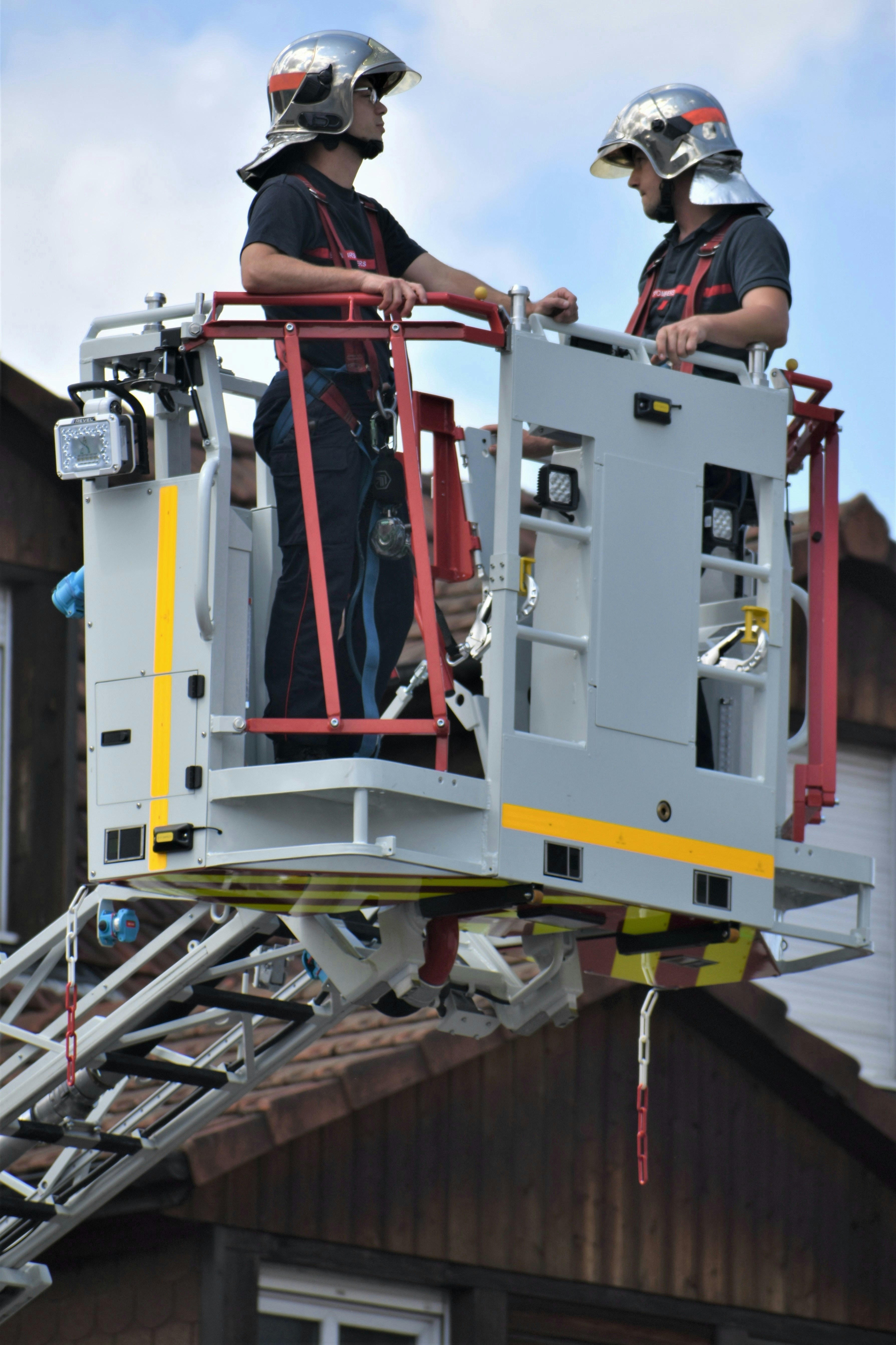 A couple of men standing on top of a fire truck