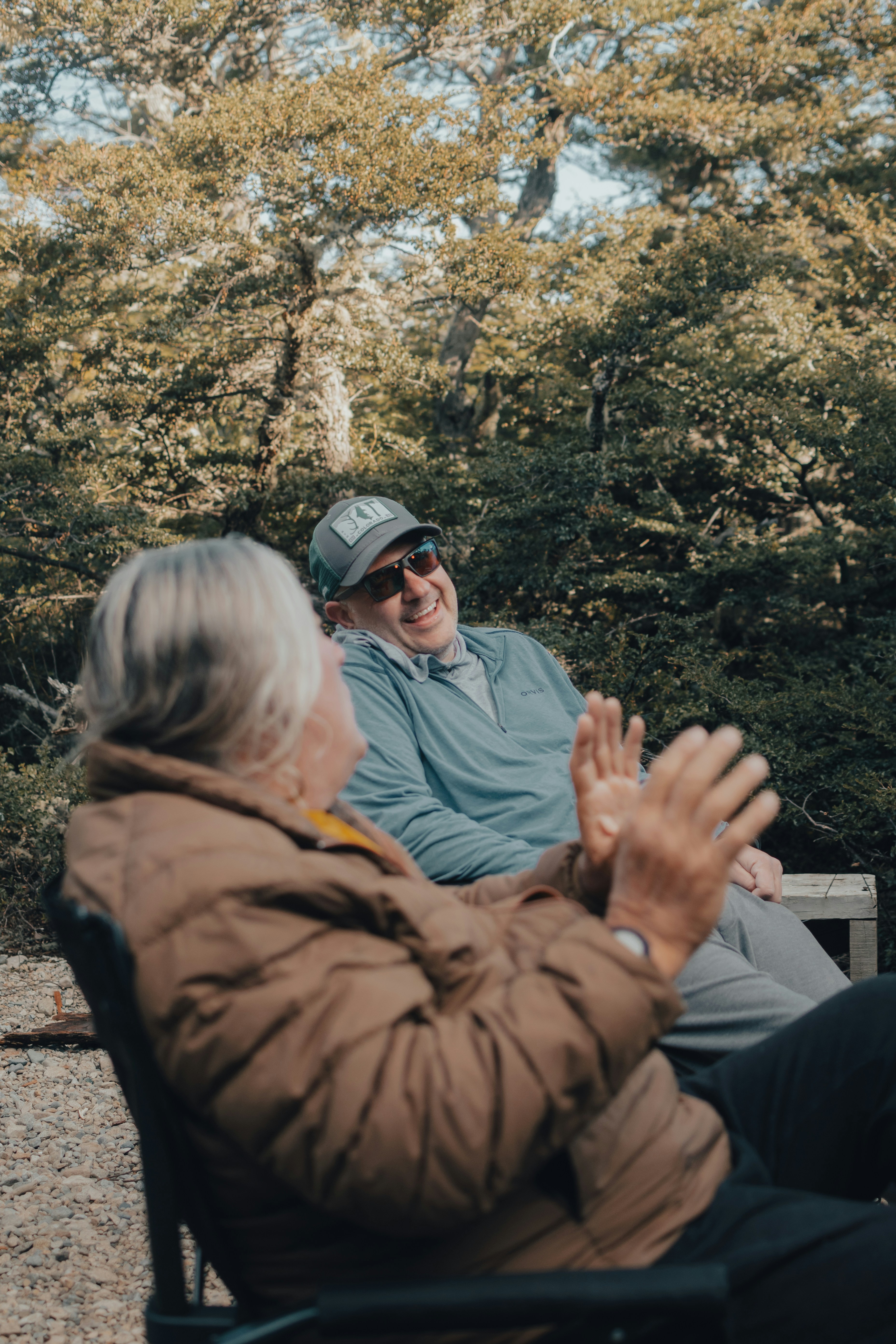 A man and a woman sitting on a bench in the woods