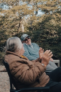 A man and a woman sitting on a bench in the woods