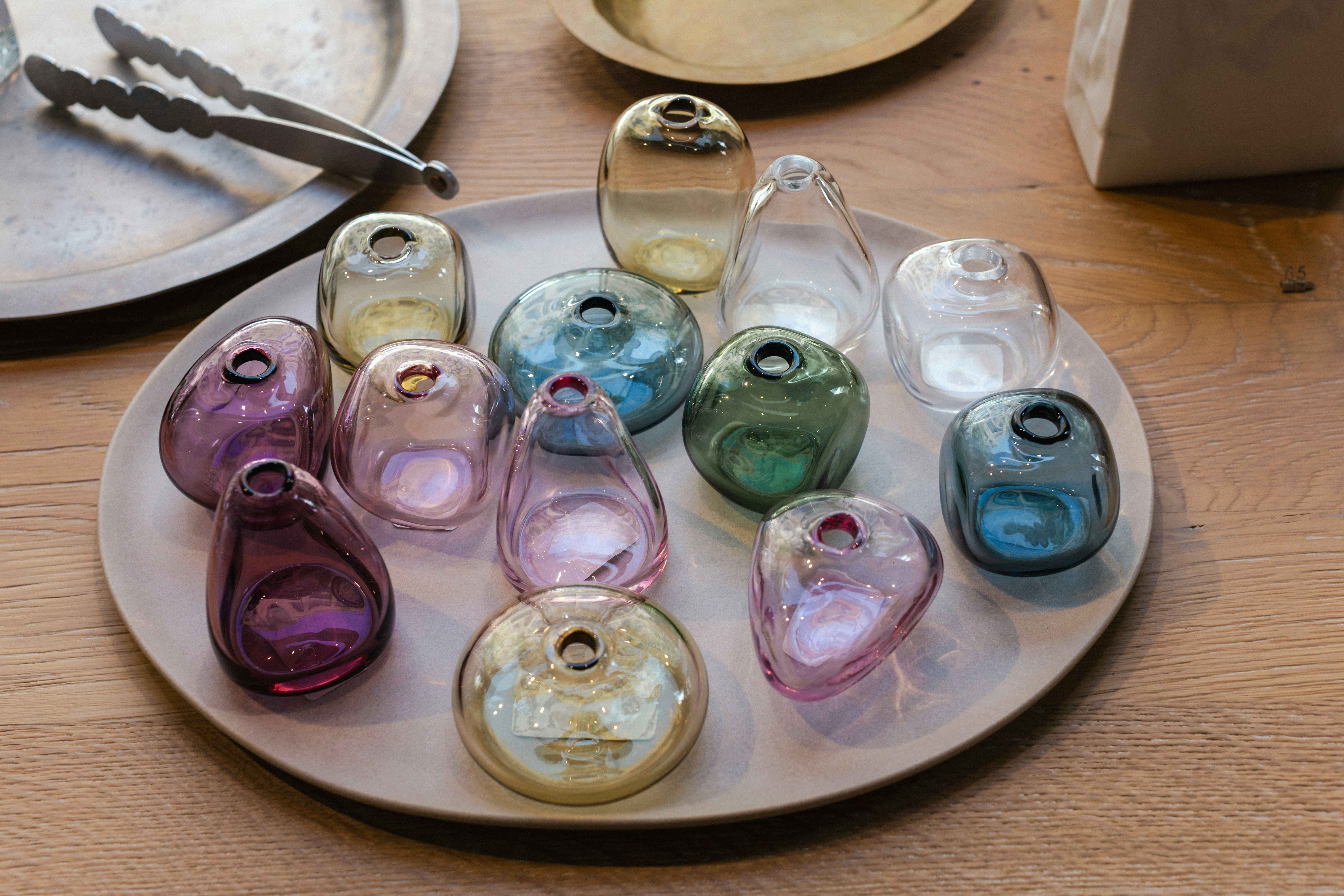 Colorful glass vases arranged on pale plate.
