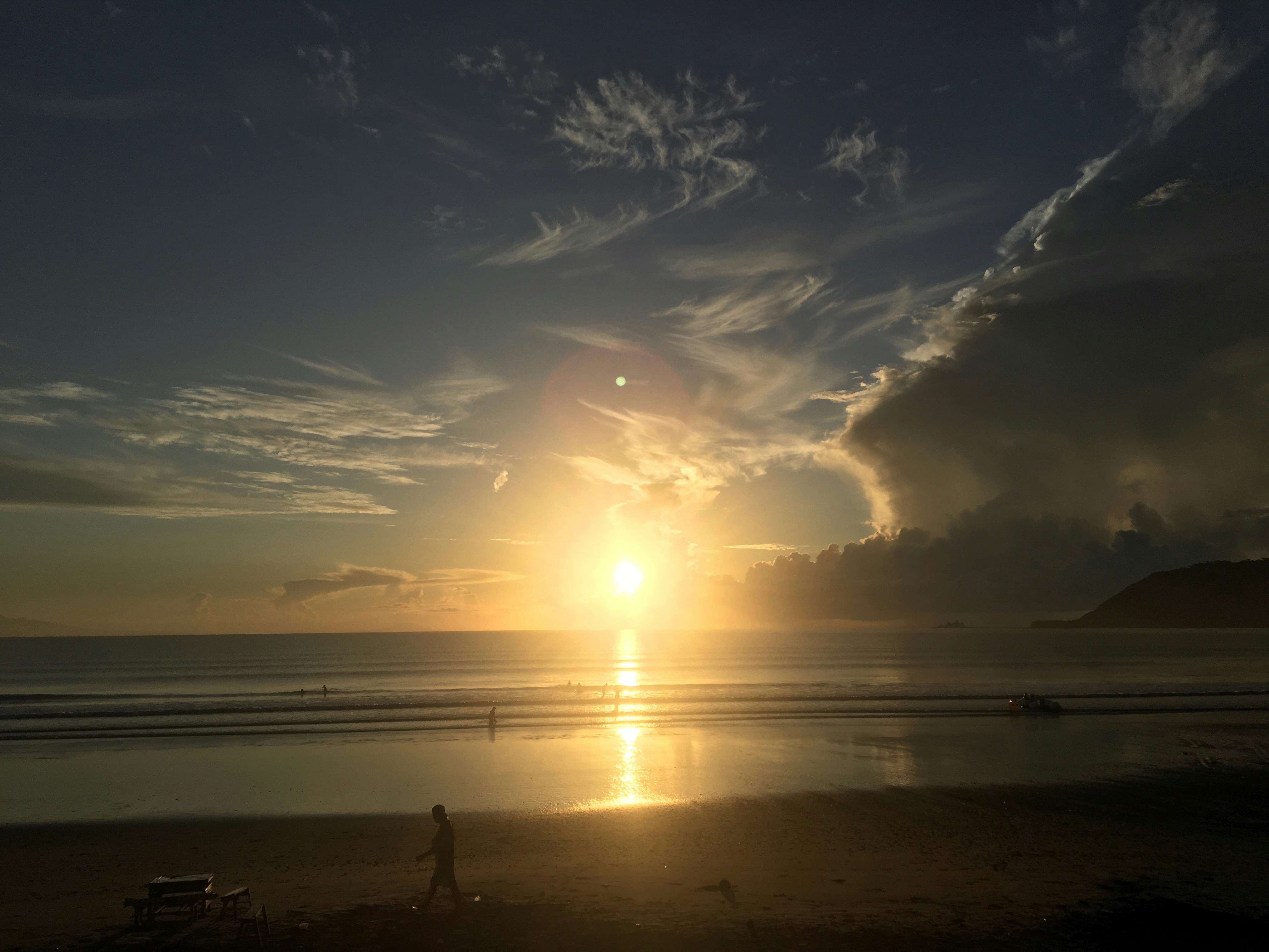 A person walking on a beach at sunset