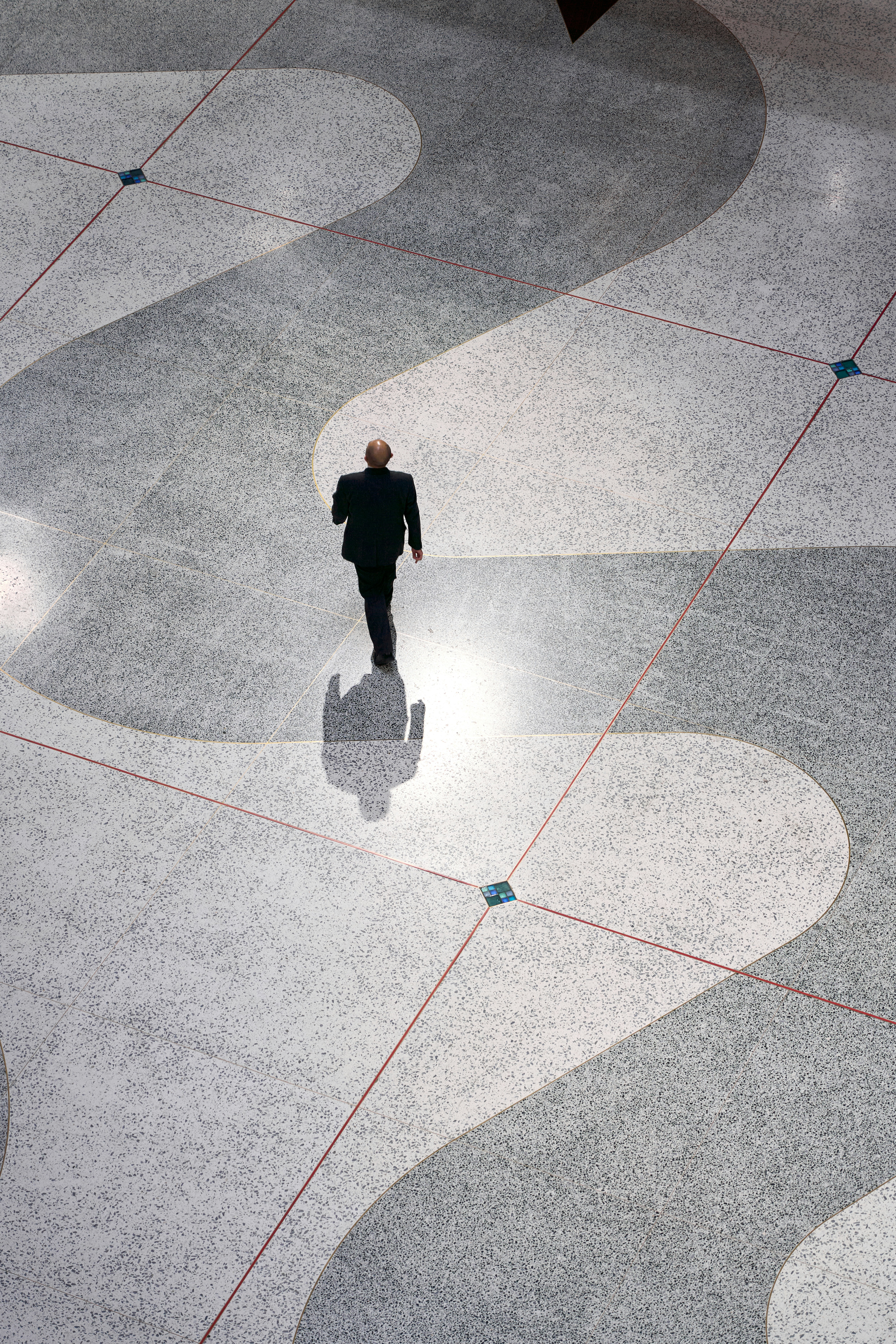 A Man In A Suit Walking Down A Sidewalk