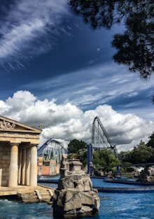 A water park with a fountain and a roller coaster in the background