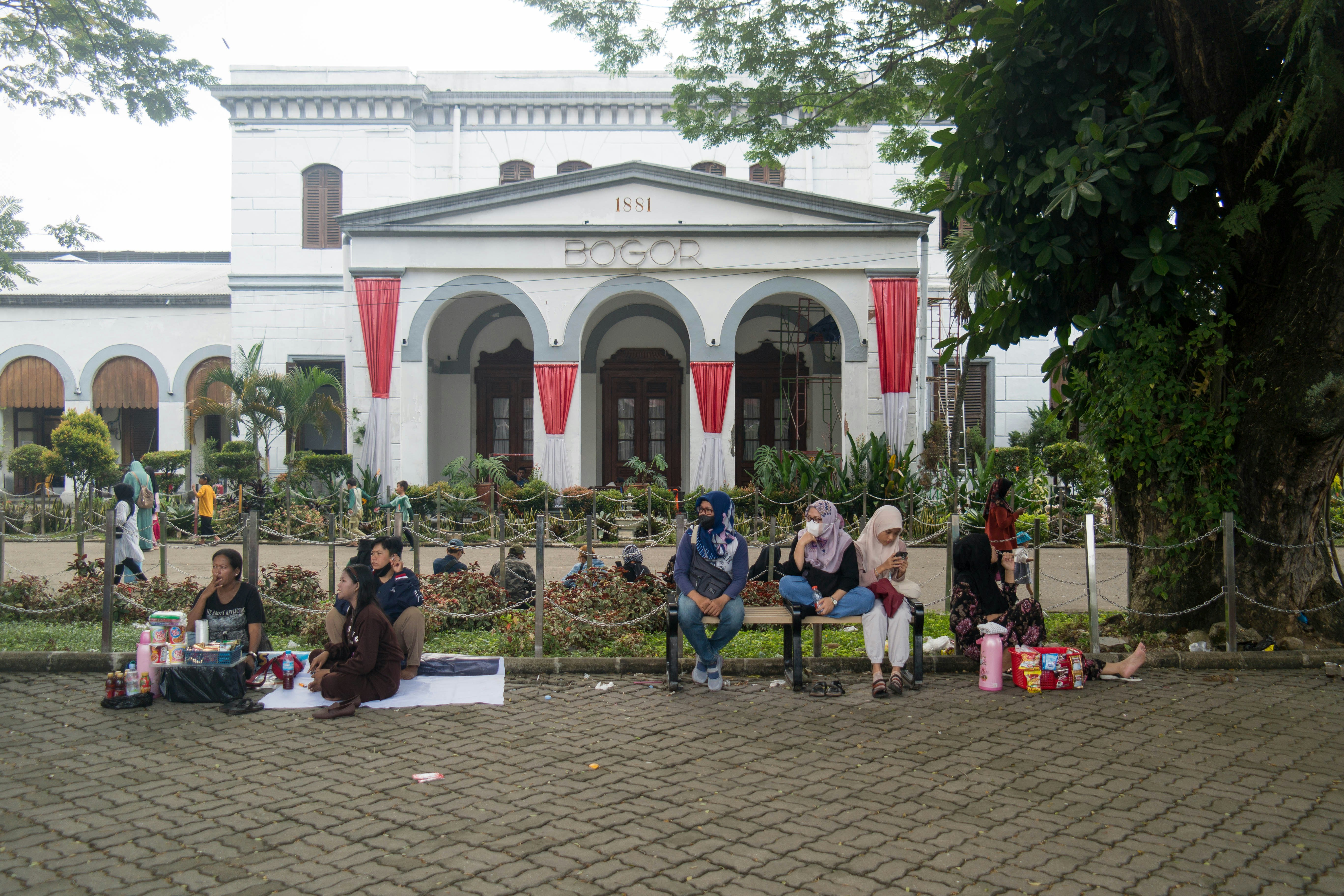 A group of people sitting on a bench in front of a building